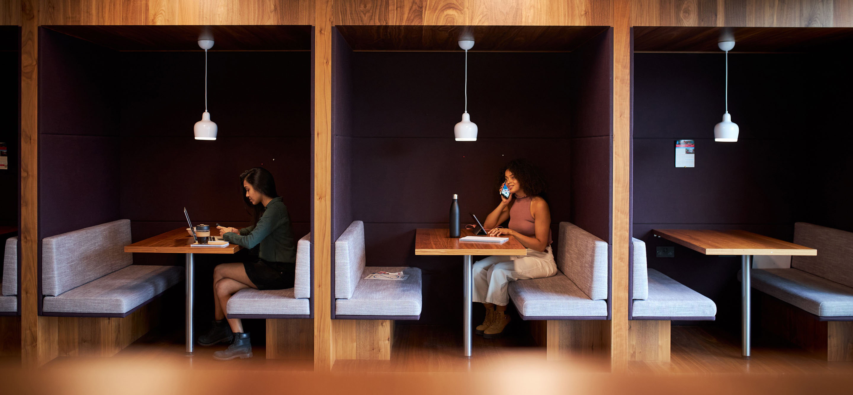 Businesswomen working in separate cubicles in modern office