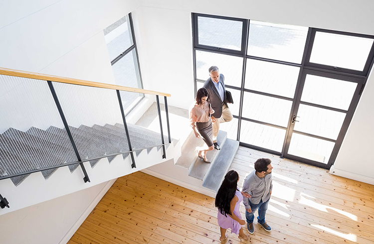Vier Menschen besichtigen ein modernes Haus, Blick von oben