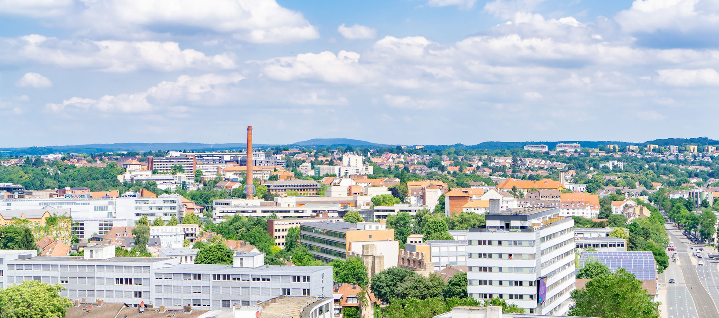 Eine lebendige Stadt mit einem klaren, sonnigen Himmel, mit verschiedenen hohen Gebaeuden, von Baeumen gesauumten Strassen in Wohngebieten