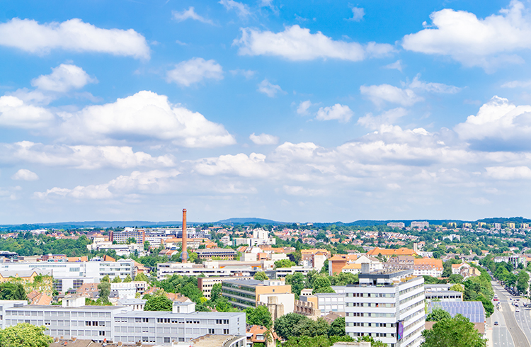 Eine lebendige Stadt mit einem klaren, sonnigen Himmel, mit verschiedenen hohen Gebaeuden, von Baeumen gesauumten Strassen in Wohngebieten