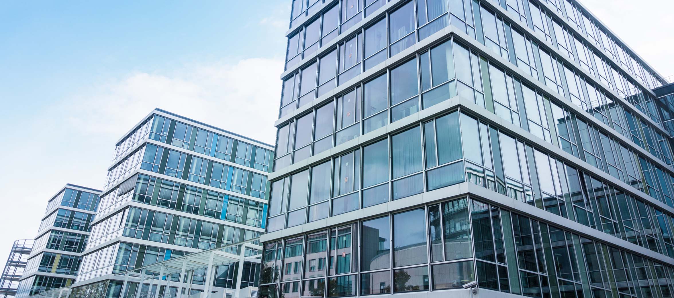 Moderne Bürogebäude mit Glasfassade unter blauem Himmel