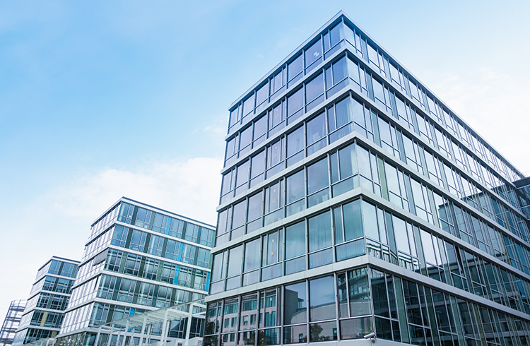 Moderne Bürogebäude mit Glasfassade unter blauem Himmel