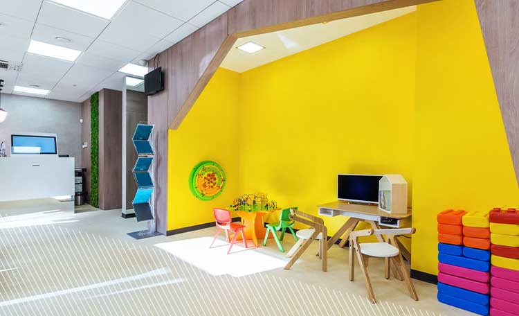 Eine moderne, gut beleuchtete Kinderspielecke mit gelben Wänden und bunten Möbeln