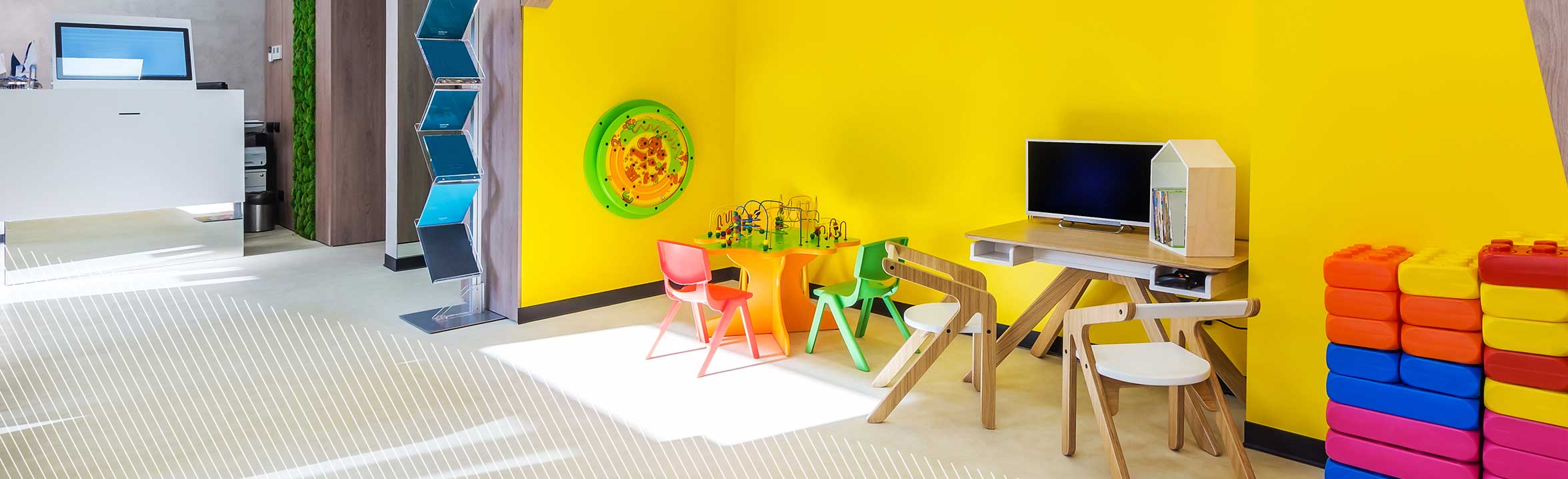 Eine moderne, gut beleuchtete Kinderspielecke mit gelben Wänden und bunten Möbeln