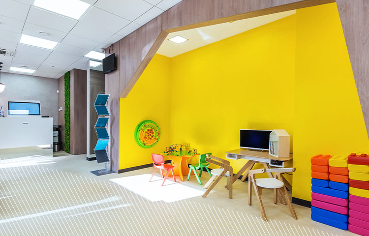 Eine moderne, gut beleuchtete Kinderspielecke mit gelben Wänden und bunten Möbeln