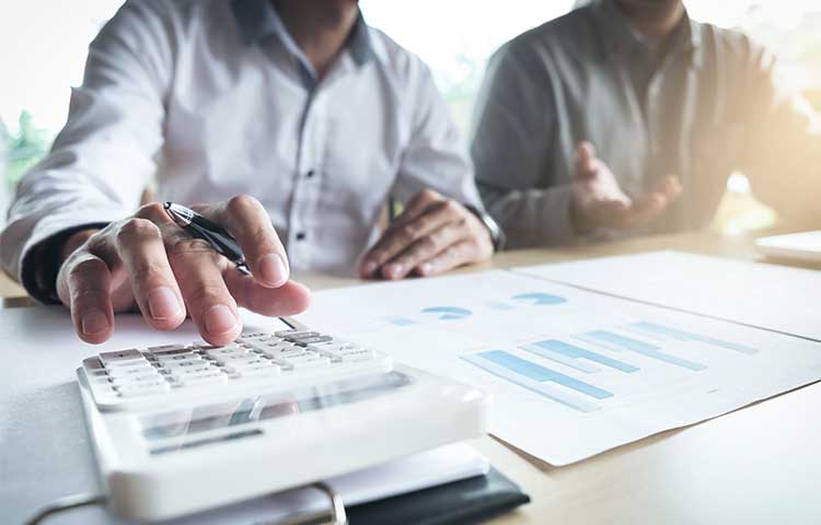 Two male colleagues calculate figures on the reports