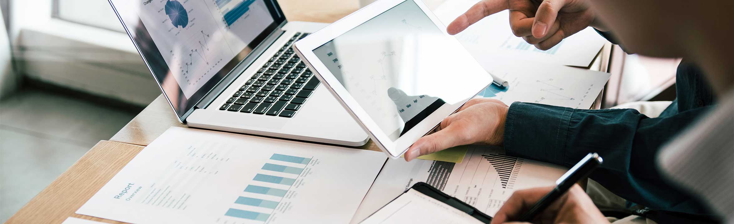 A team of diverse colleagues uses laptop and tablet to work on a project together