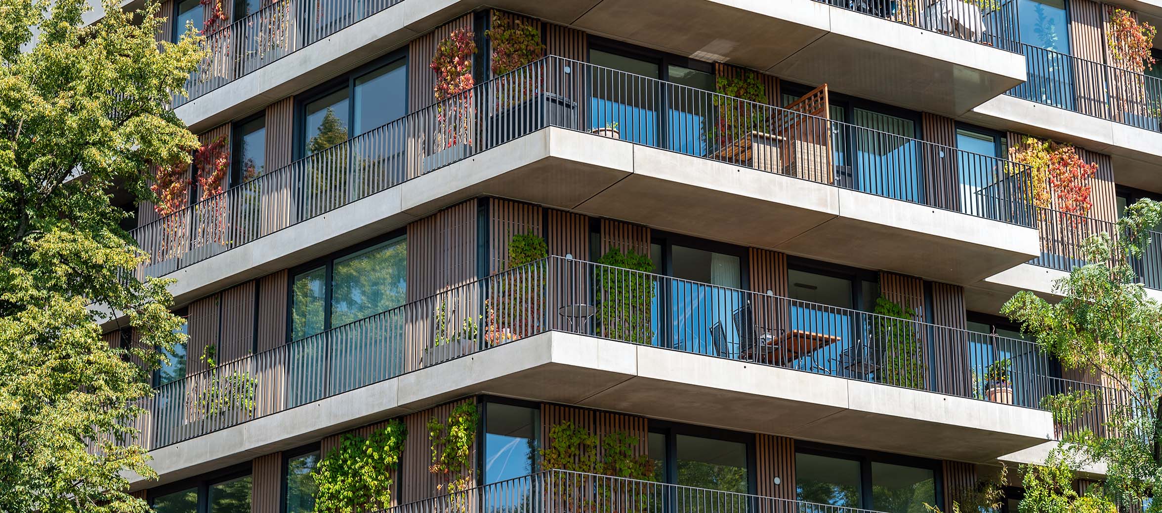 A modern residential building with big balconies with green plants