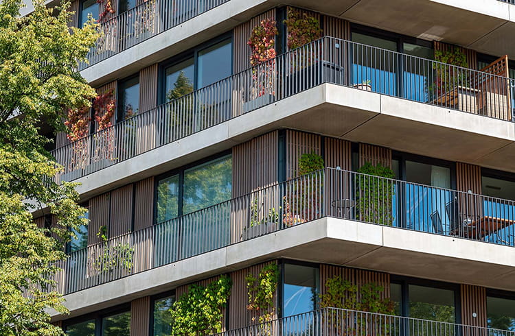 A modern residential building with big balconies with green plants