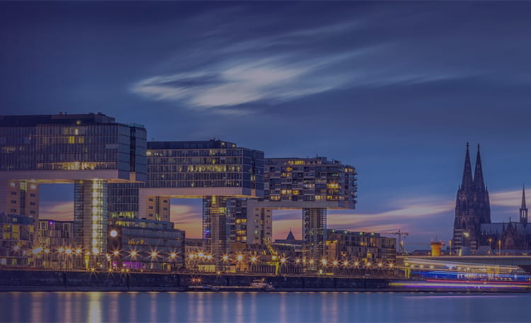 Cologne skyline with river, crane houses and dome at night