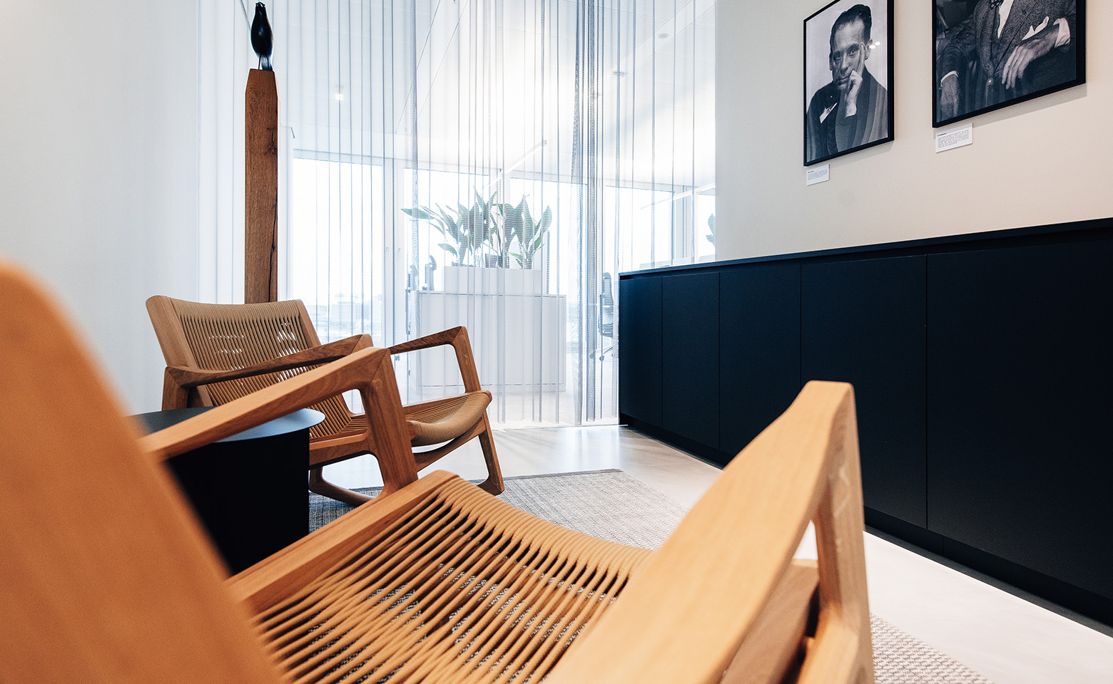 Eine Hamburger Bueroecke mit 2 Holzschaukelstuehlen, einem schwarzen Schrank und Postern an der weissen Wand