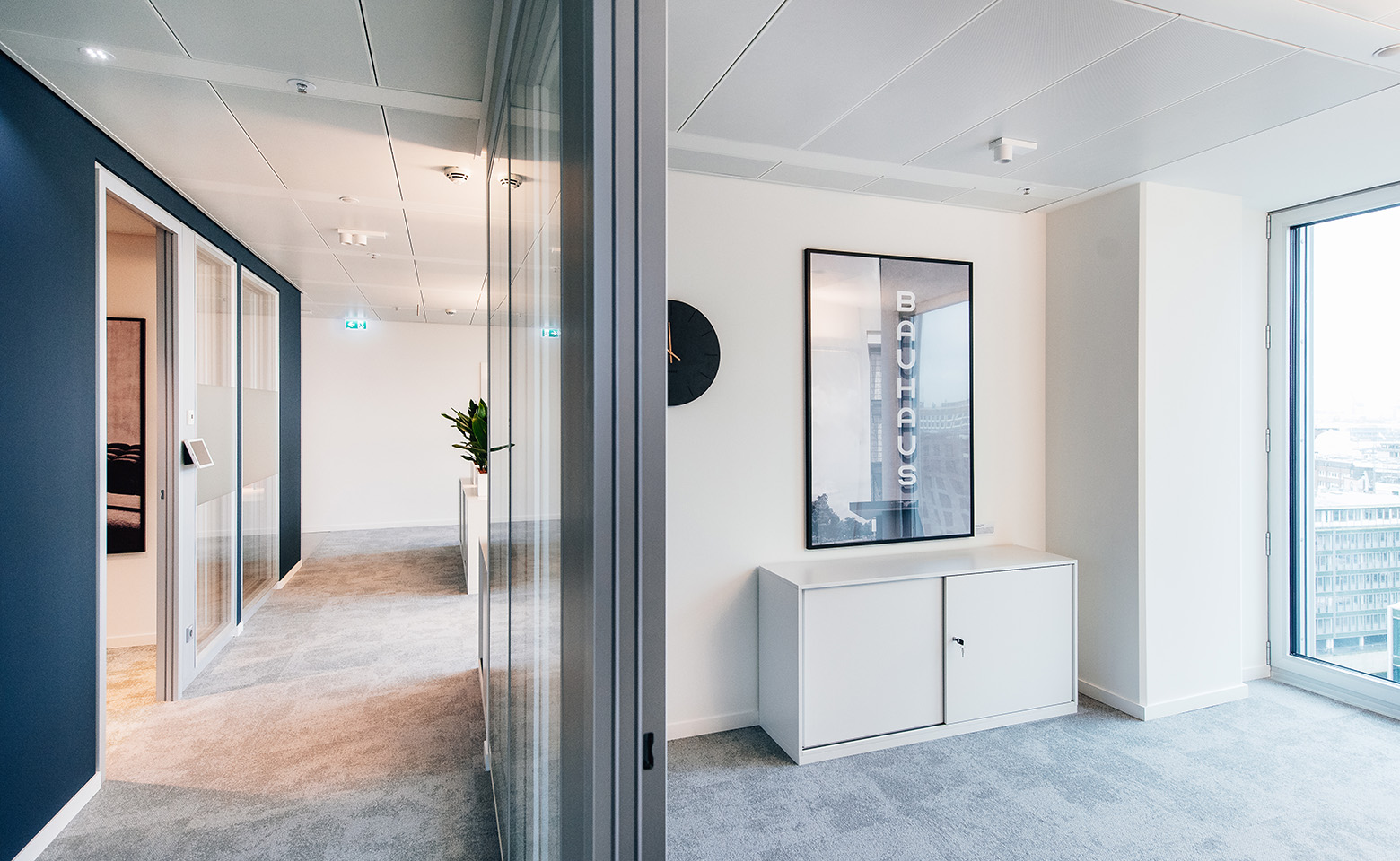Hallway with dark blue wall, a white small cabinet and a wall poster in Hamburg office