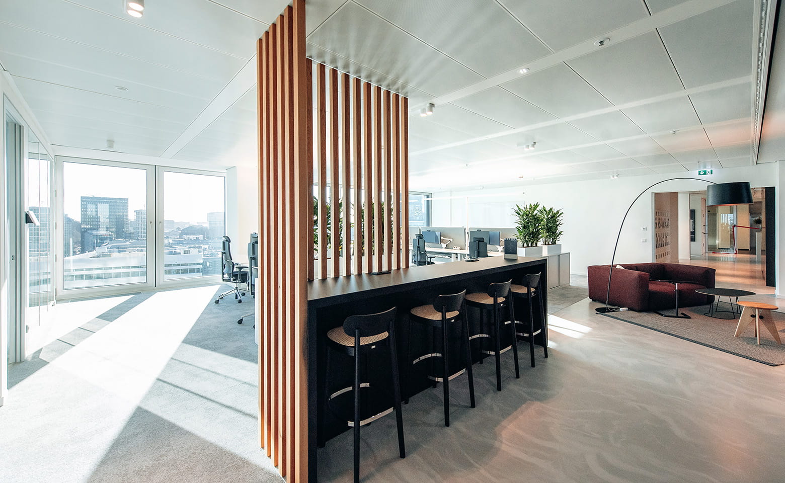 Hamburg office with big windows with view, dining corner with high chairs, lounge area with dark red sofa