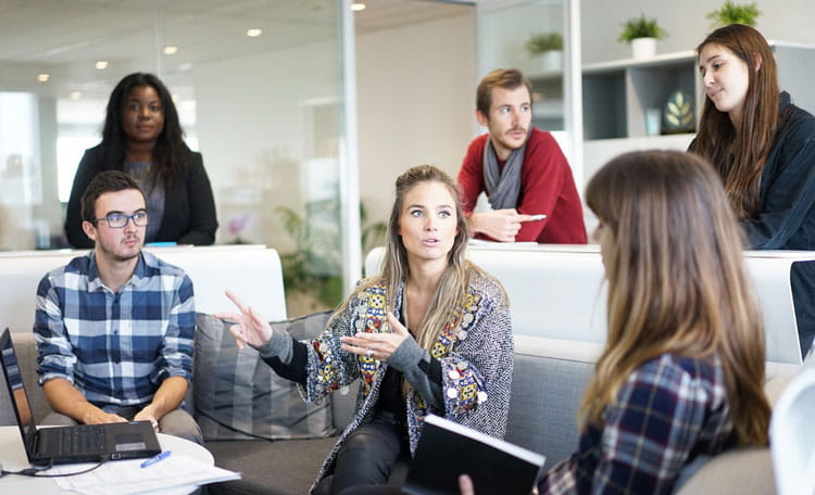 woman on sofa talking to colleagues gathered around